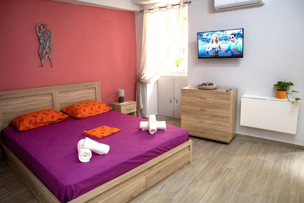 埃尔莫波利斯Maya Studio的一间卧室配有紫色的床和墙上的电视