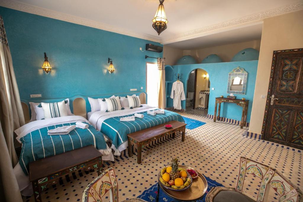 梅尔祖卡Riad Jouba的一间卧室设有两张床和一张带一碗水果的桌子。