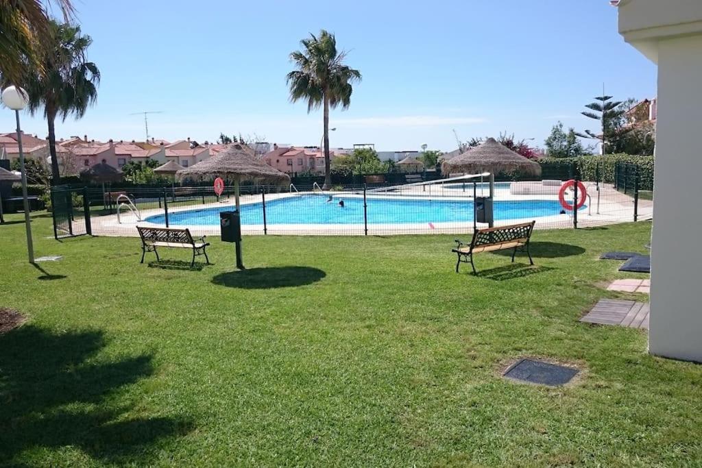 贝莱斯Chalet Cerca de la playa registro VFT/MA/50455的两个长椅坐在游泳池附近的草地上