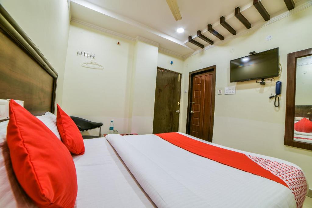 KhammamOYO Surya Teja Residency的一间卧室配有一张带红色枕头的床和电视。