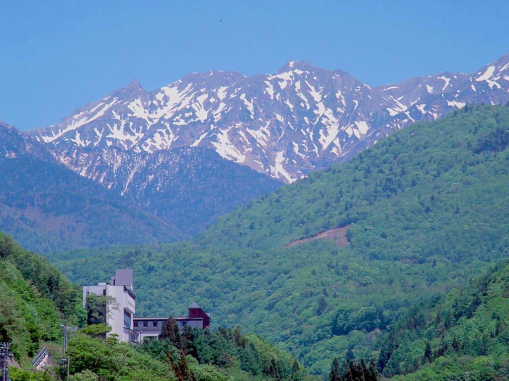 高山惠高庄山野酒店的山丘上的建筑,背景是山脉