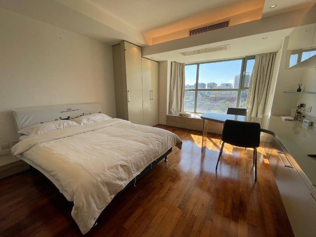北京Beijing Elegant Seasons Park Apartment的一间卧室配有一张床、一张桌子和一个窗户。