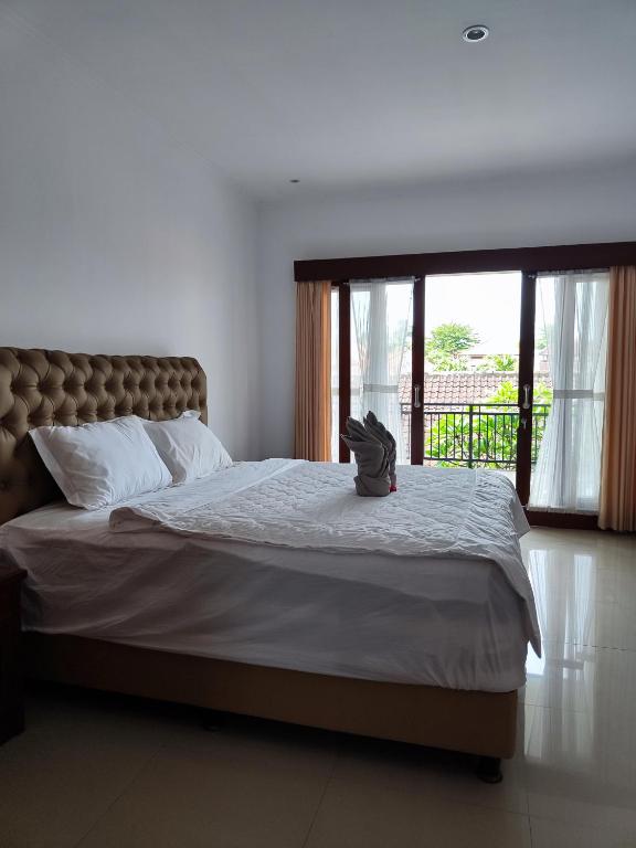 沙努尔LA Homestay sanur的一间带大床和大窗户的卧室