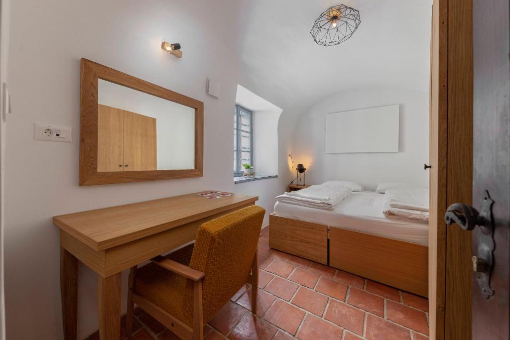 克拉尼Apartma Jenkova rezidenca的一间卧室配有书桌和一张带镜子的床