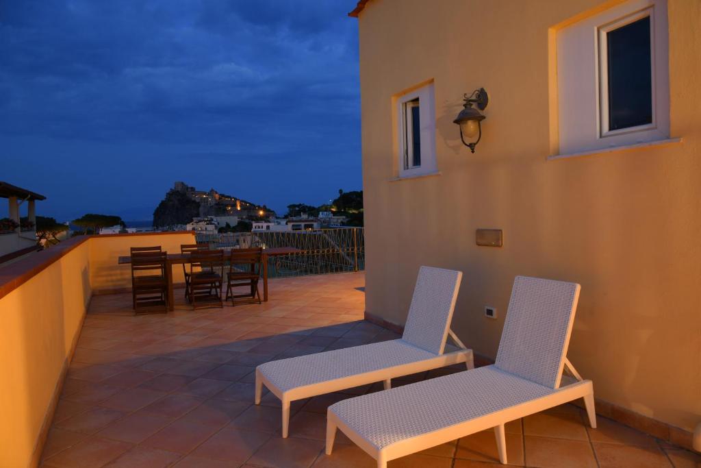 伊斯基亚艾尔博古大西洋酒店的晚上阳台上配有两把椅子和一张桌子