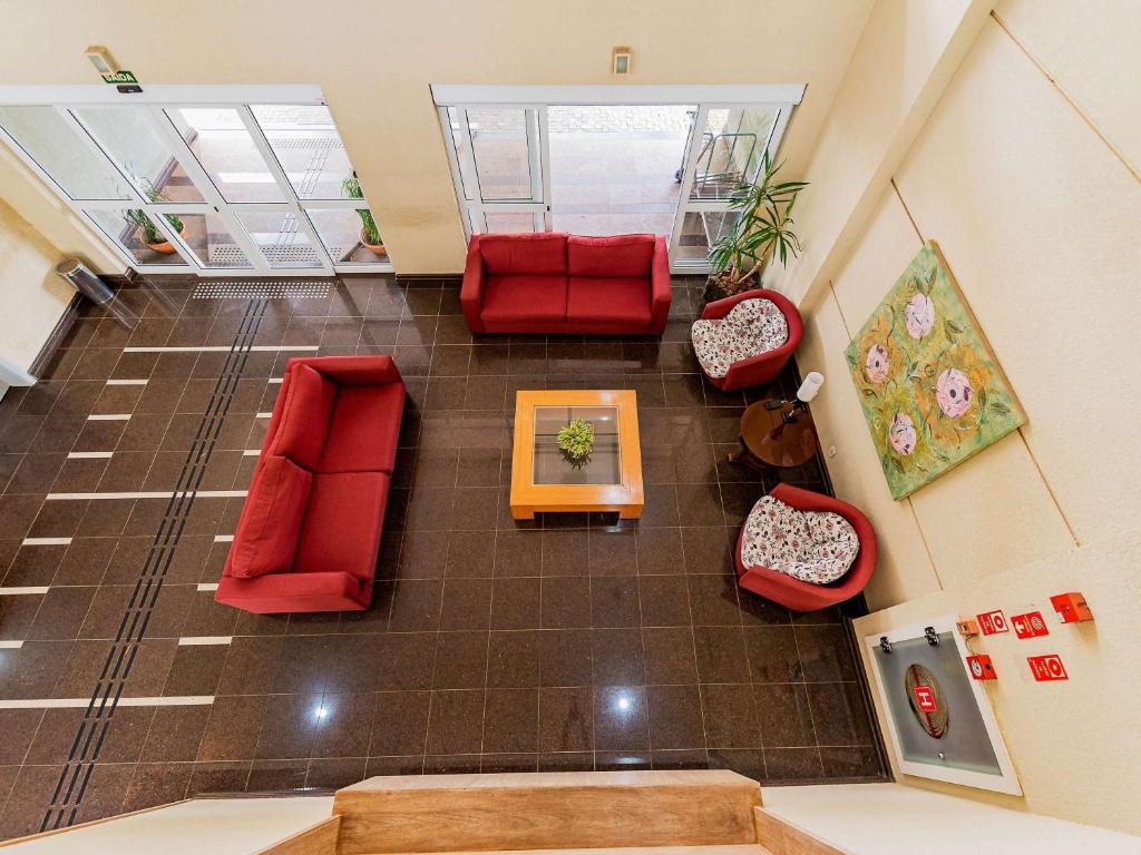 坎皮纳斯Ibis Styles Campinas Alphaville的享有带红色椅子和桌子的客厅的顶部景色。