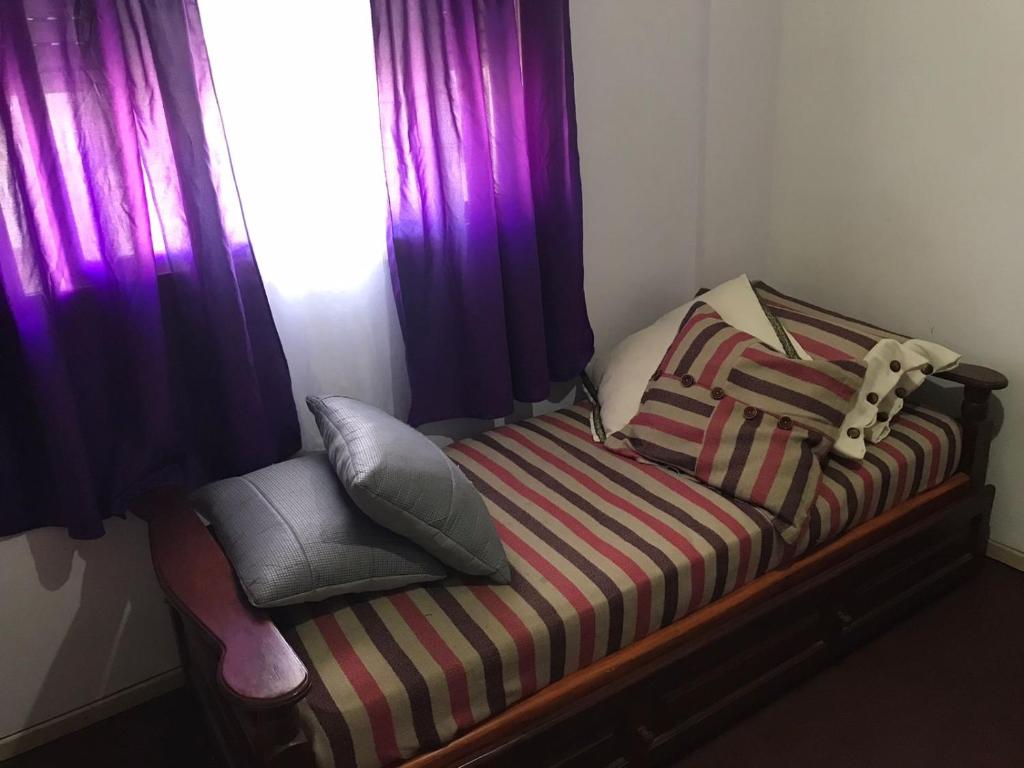 坦迪尔Habitacion Super Comoda en Casa Particular的一间卧室配有一张紫色窗帘的床