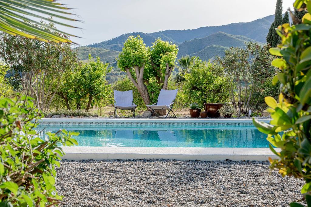 阿洛拉Finca El Limonar的一个带两把椅子的游泳池,并有树木和山脉