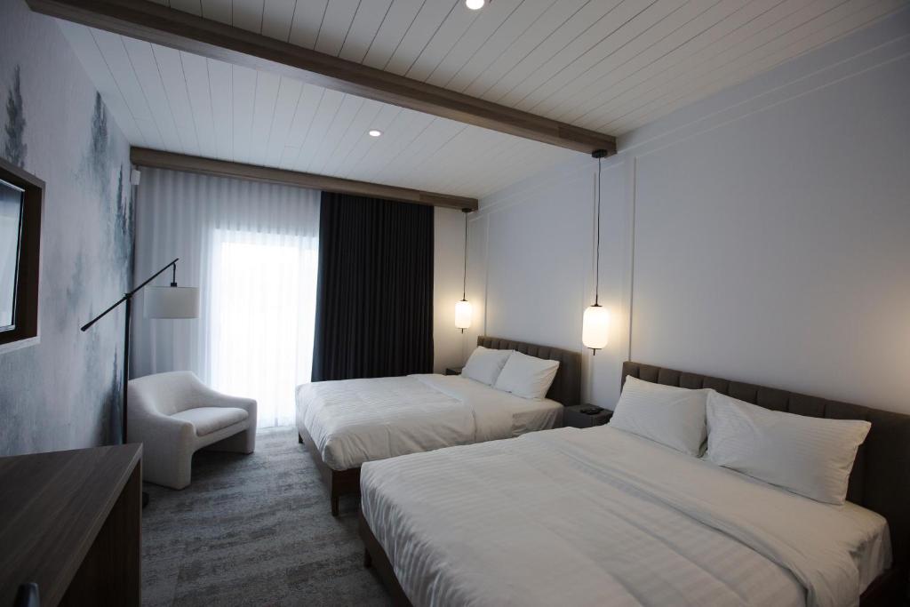 Saint-AmbroiseHotelia的酒店客房,配有两张床和椅子