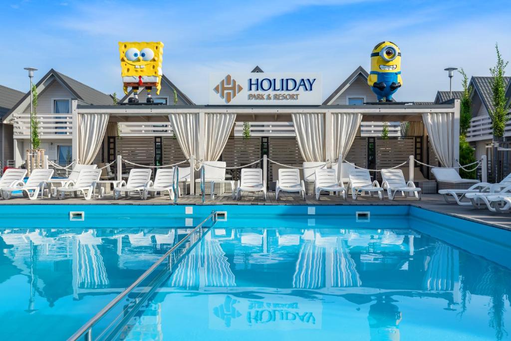 格里兹鲍Holiday Park & Resort Grzybowo的一个带椅子的酒店游泳池和酒店标志
