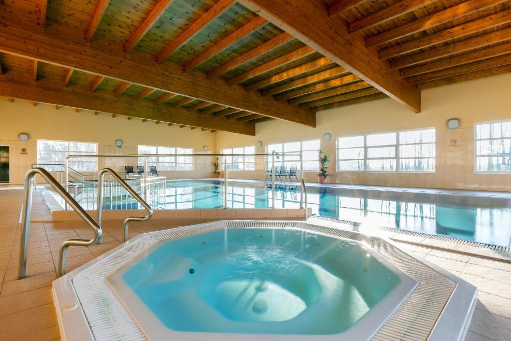 达布基BURSZTYN - BERNSTEIN SPA & Wellness的大楼内带热水浴池的大型游泳池