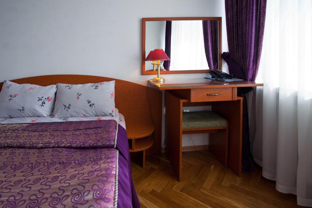 利沃夫赫特曼酒店的一间卧室配有一张床和一张带镜子的书桌