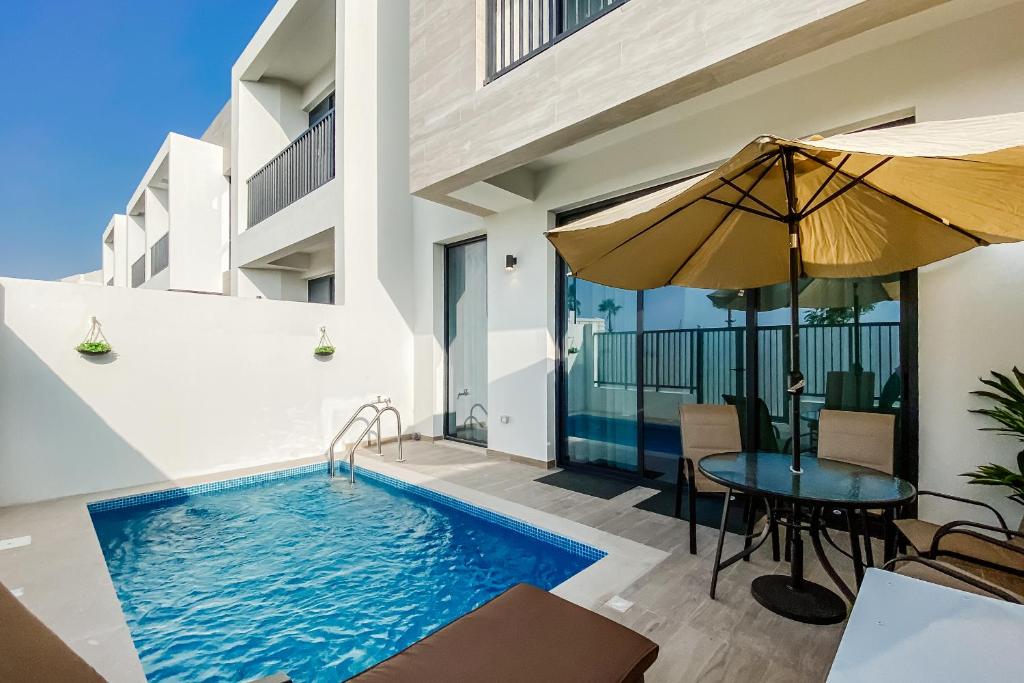 拉斯阿尔卡麦Luxury Villas with Beach Access by VB Homes的一座房子,里面设有游泳池、桌子和遮阳伞