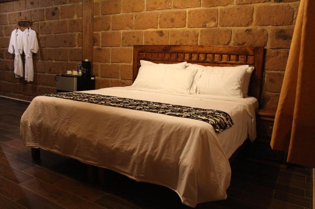 特科早特拉Hotel Real Nirvana的砖墙房间的一个床位