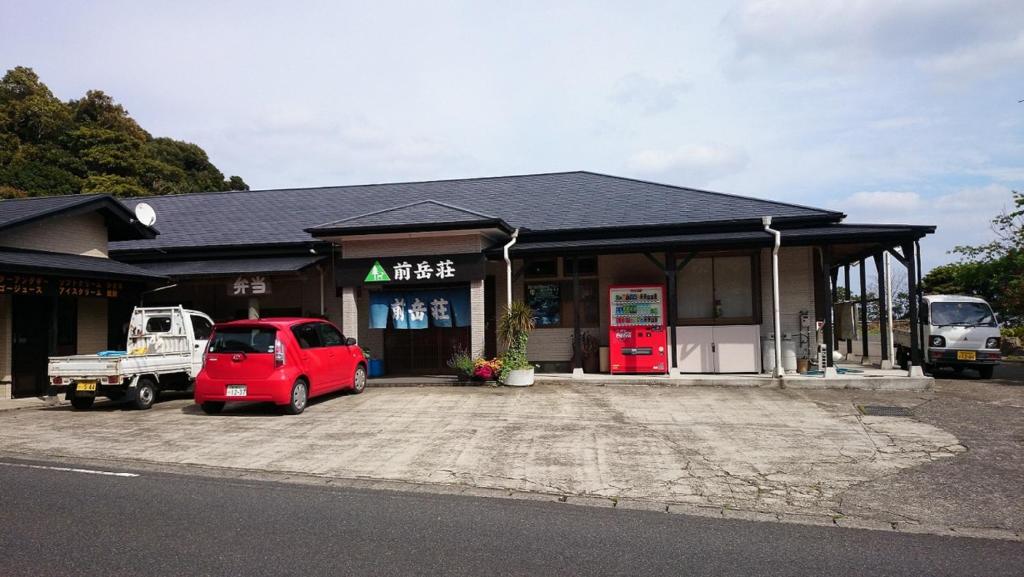 屋久岛Maetakeso的前面有一辆红色汽车的建筑