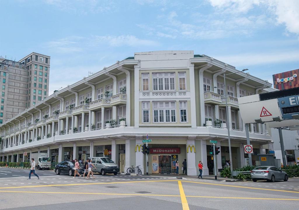 新加坡Hovoh Boutique Service Apt的一条有汽车的城市街道上白色的大建筑