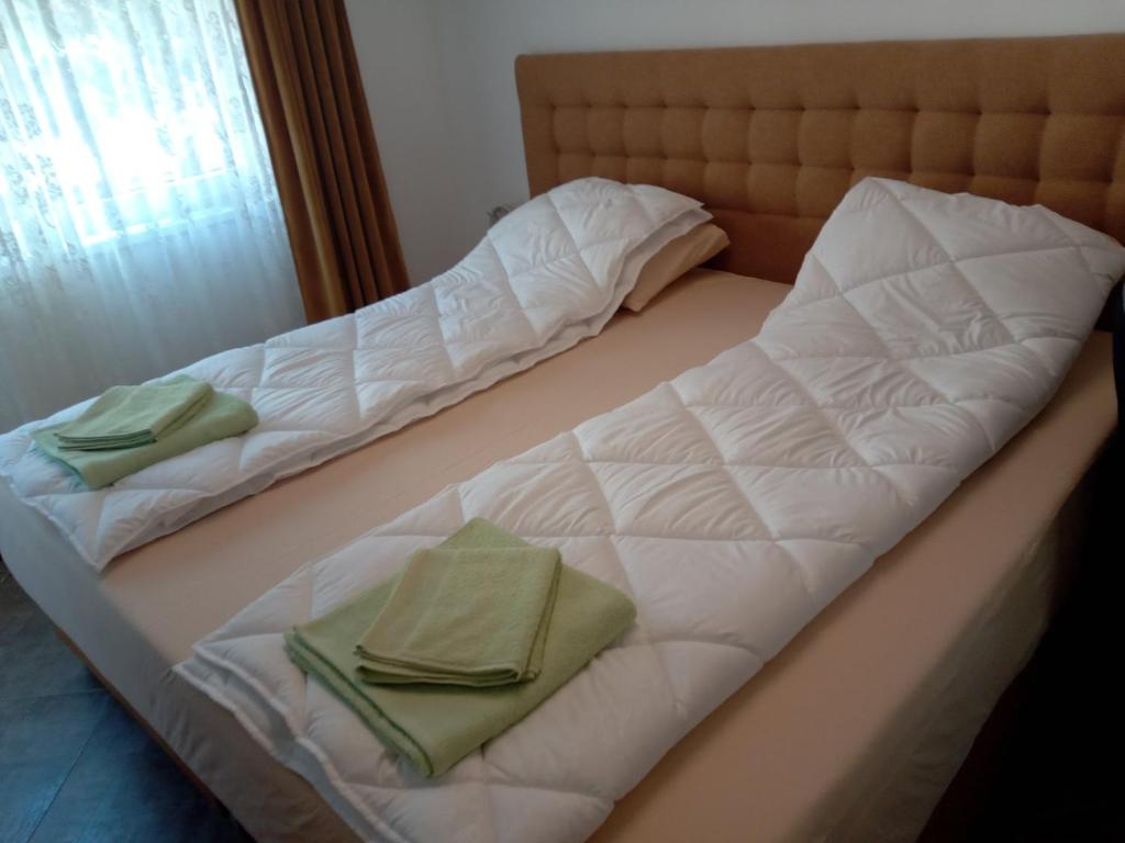 瓦列沃Stan na dan Sale 014的两张床,配有白色床单和绿色毛巾