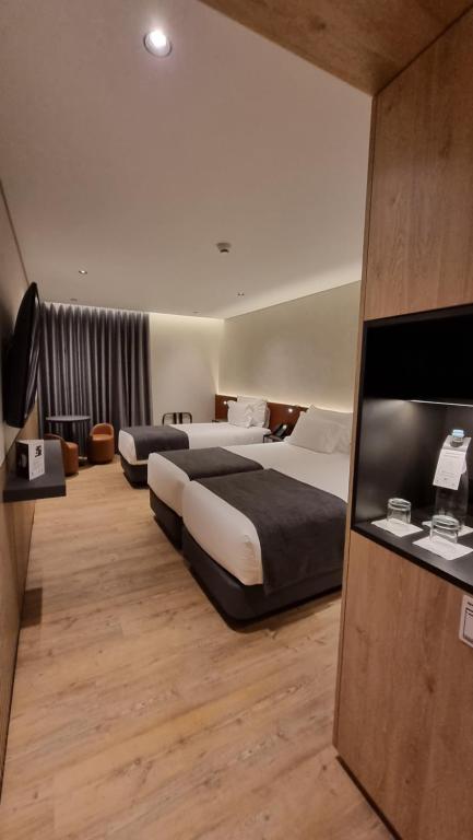 里斯本Hotel Principe Avila的酒店客房设有两张床和一台平面电视。