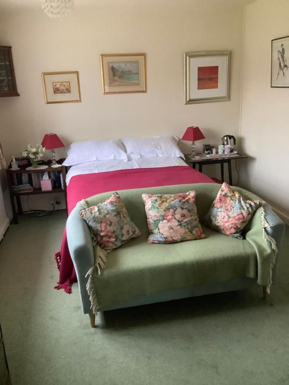 霍尔特Garwood House的一间卧室配有一张带绿沙发及枕头的床