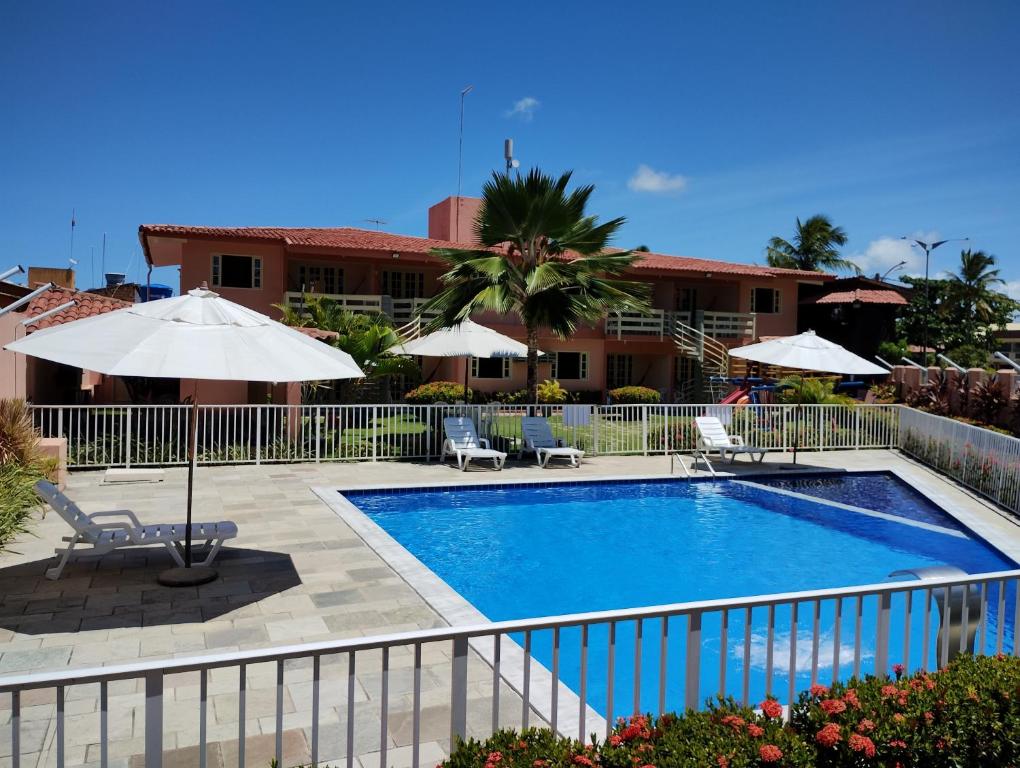 嘎林海斯港波萨达日卡昂特索豪斯普尔托公寓的酒店前方的游泳池配有椅子和遮阳伞