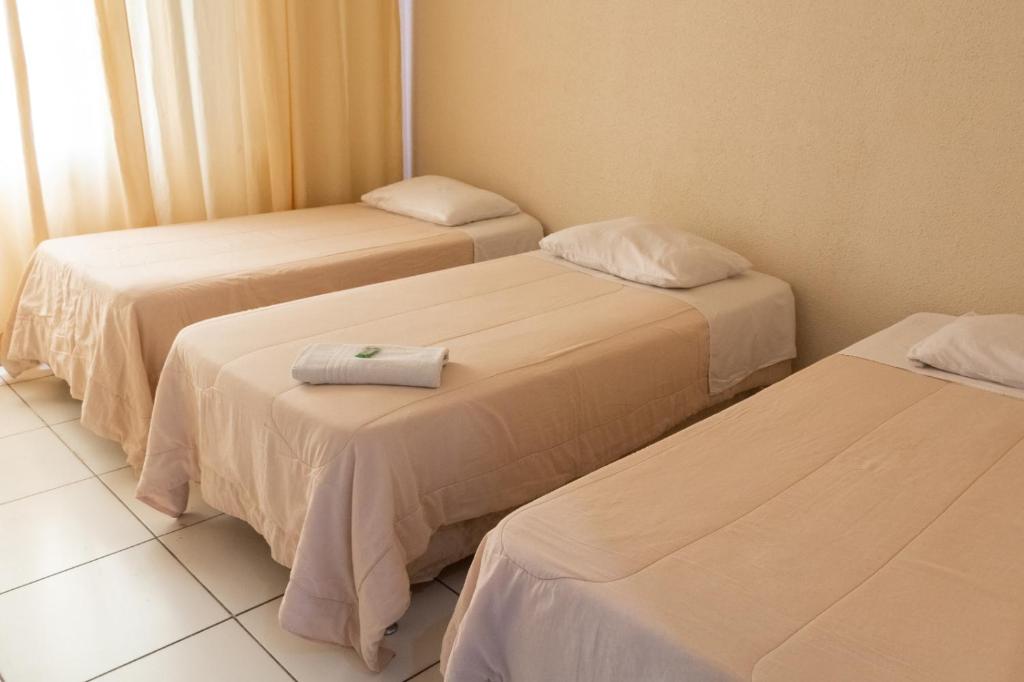 巴乌鲁ALVORADA PALACE HOTEL的一间设有三张床的客房,备有毛巾