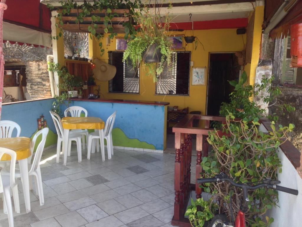 萨尔瓦多Nega Maluca Guesthouse的一间设有白色椅子和桌椅的餐厅