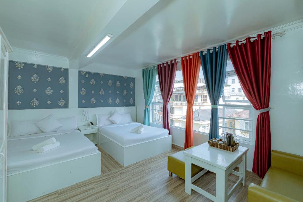 大叻Ken's Backpackers Hotel的客房设有两张床、一张桌子和窗户。