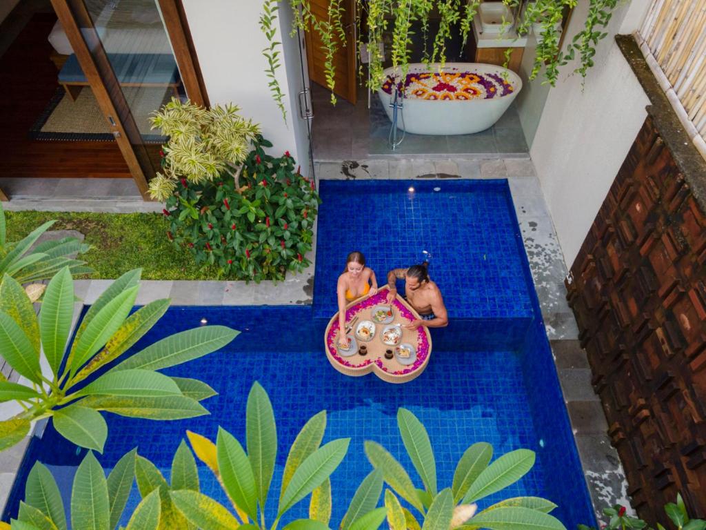 坎古Teratai Villa Canggu by Ini Vie Hospitality的两个女孩在带冲浪板的游泳池玩耍