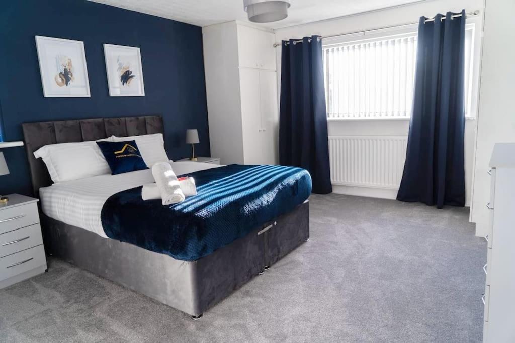 索利赫尔Solihull 5 Bed Home near NEC/Bham airport/JLR/HS2的一间卧室配有一张带蓝色墙壁的大床