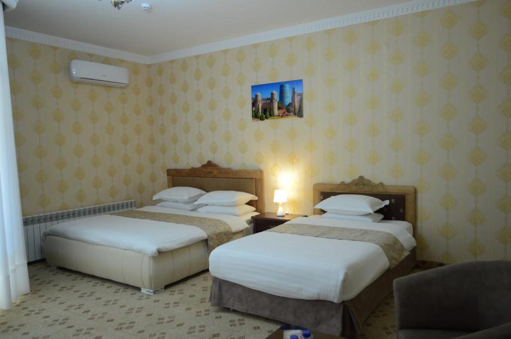 布哈拉KABIR HOTEL的两张位于酒店客房的床铺,配有黄色壁纸