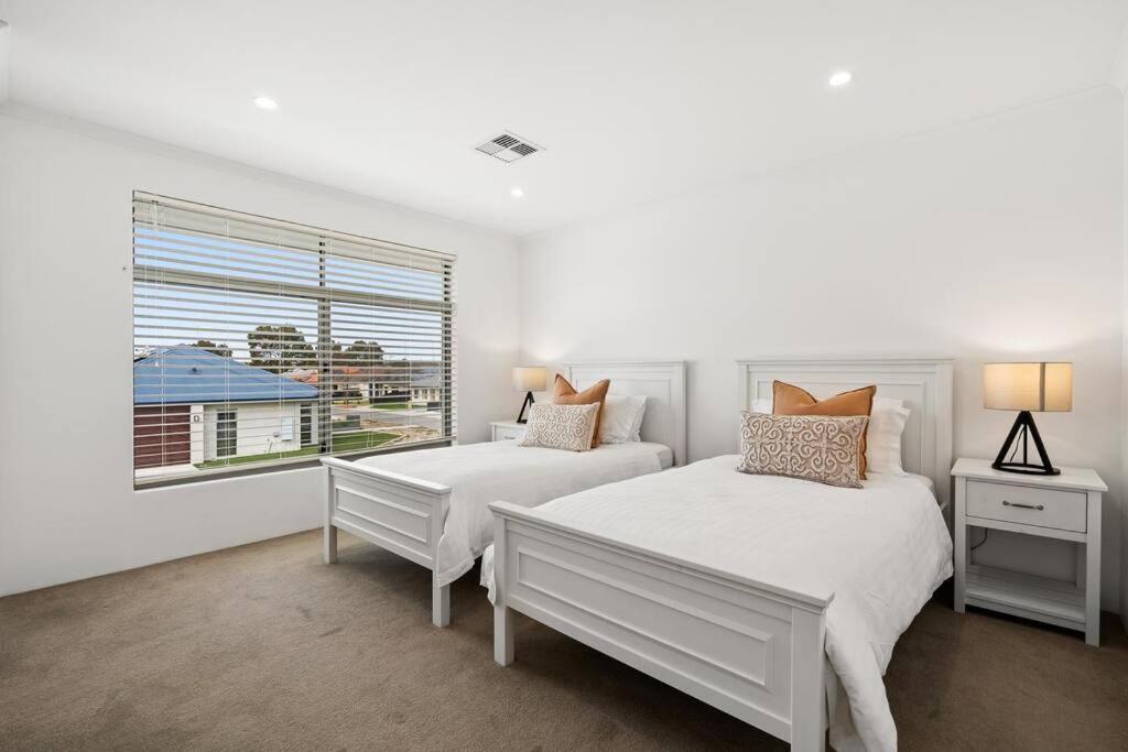 珀斯Modern Minimalistic Home 3BR的一间白色卧室,配有两张床和窗户