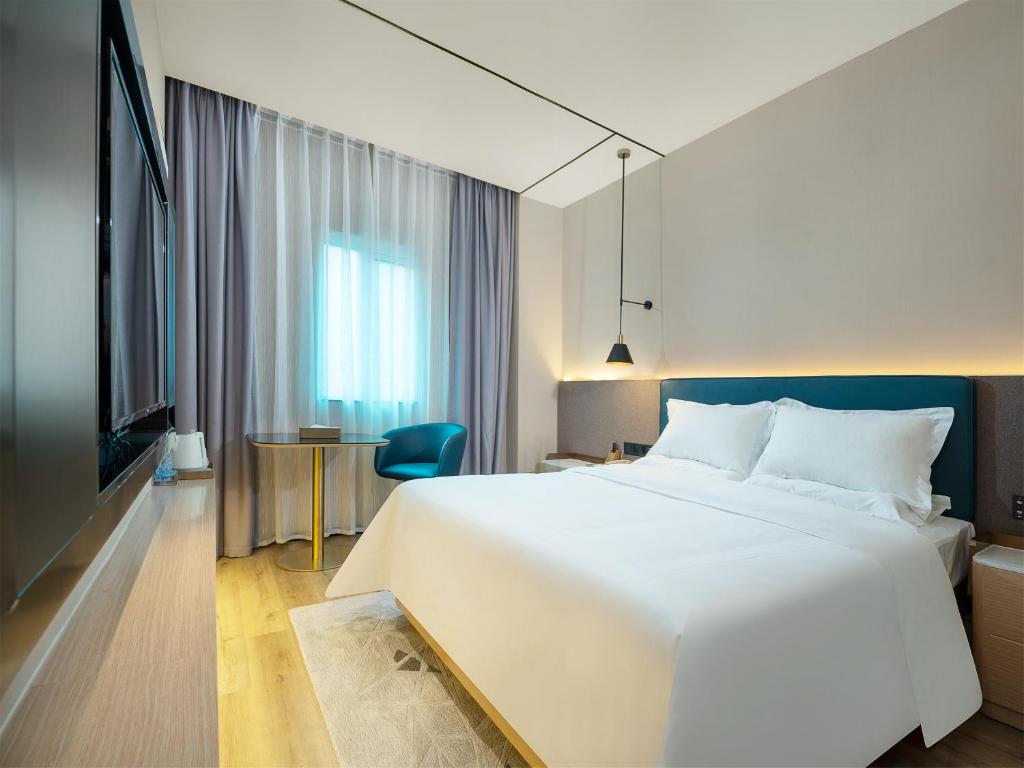 广州潮漫酒店(广州石井城市广场小坪地铁站店)的卧室配有一张白色的大床和一张桌子