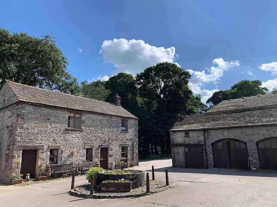 Millers DaleThe Old Stables, Near Bakewell的一座古老的石头建筑,设有两个车库