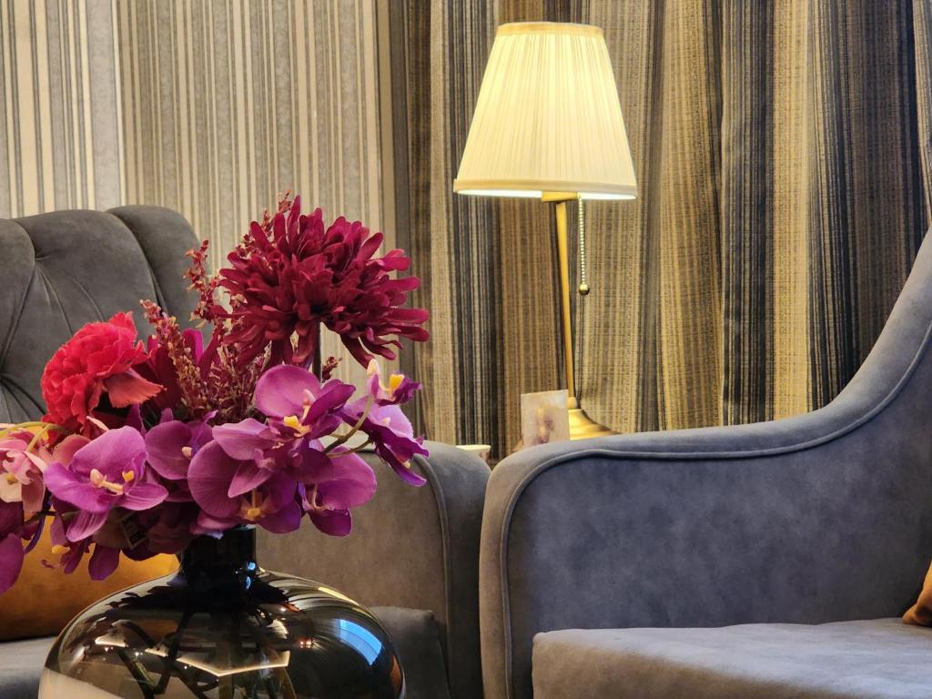 吉达Shaty Alhayat Hotel Suites的椅子旁装满紫色花的花瓶