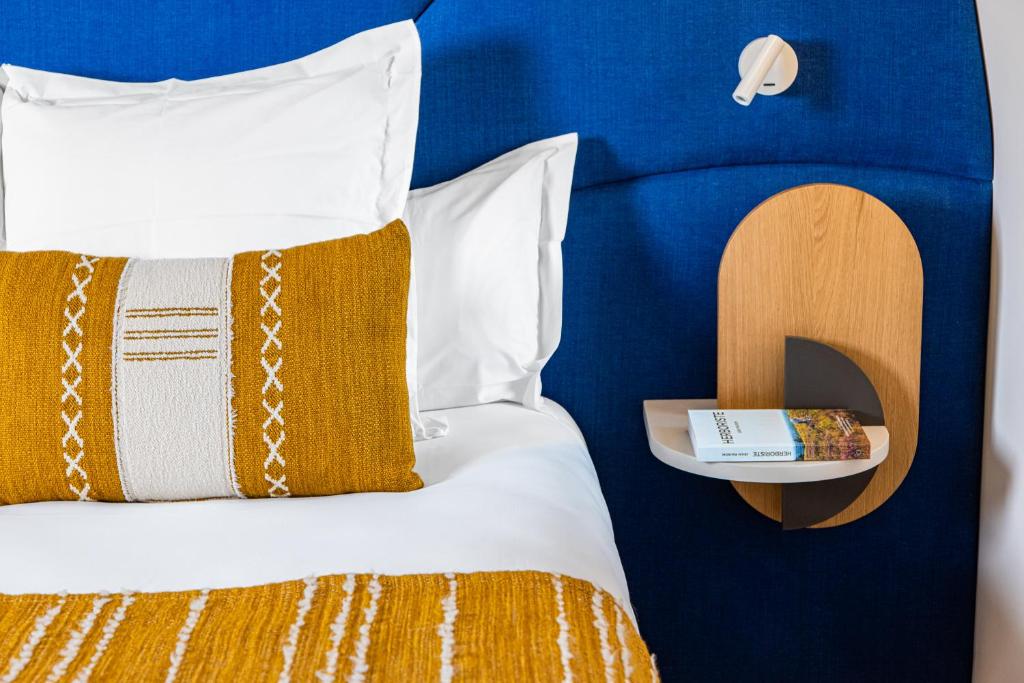 AltillacCueillette的一张带橙色和白色枕头的床和床头柜