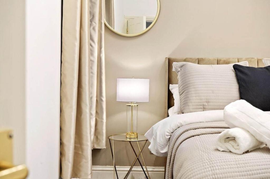 KentStylish 2BR Luxury Retreat with 65" Smart TV的一间卧室配有一张带灯和镜子的床