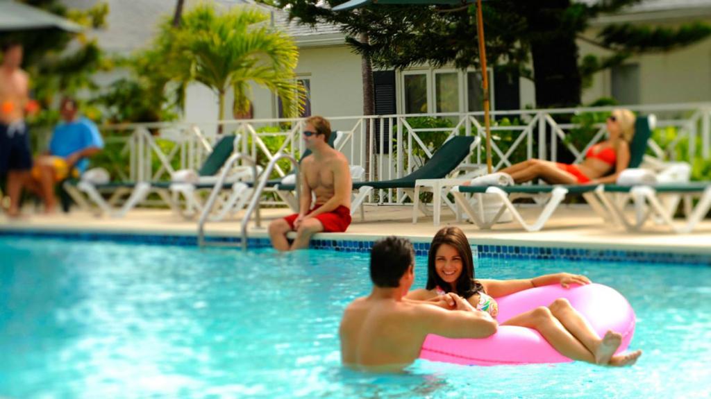 拿骚天堂岛湾景套房度假村的一群人在游泳池里,有粉红色的木筏
