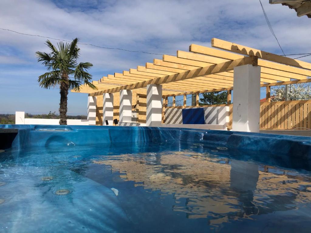PázmándfaluBorbara Apartman的一个带木制凉亭和棕榈树的游泳池
