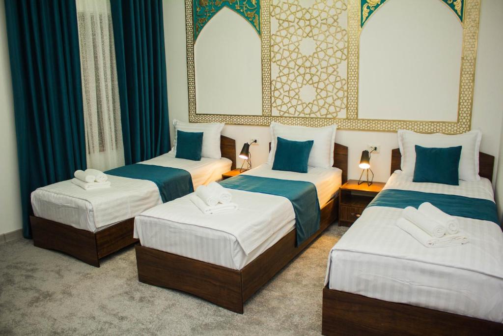 布哈拉Jahangir Boutique Bukhara的带蓝色窗帘的客房内的三张床