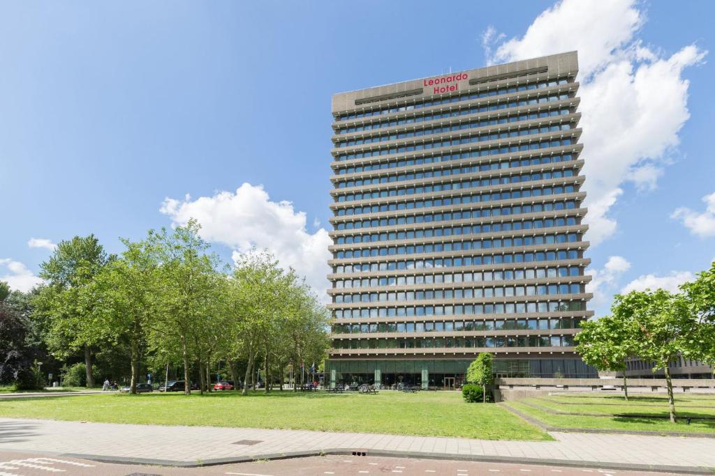 阿姆斯特丹Leonardo Hotel Amsterdam Rembrandtpark的一座高大的建筑,前面有一个公园