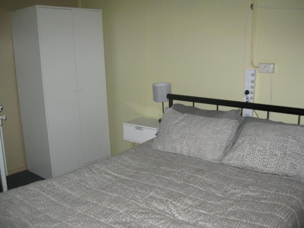 温顿Australian Hotel Winton Budget Hotel Accommodation的一间卧室配有一张床和一张桌子上的台灯