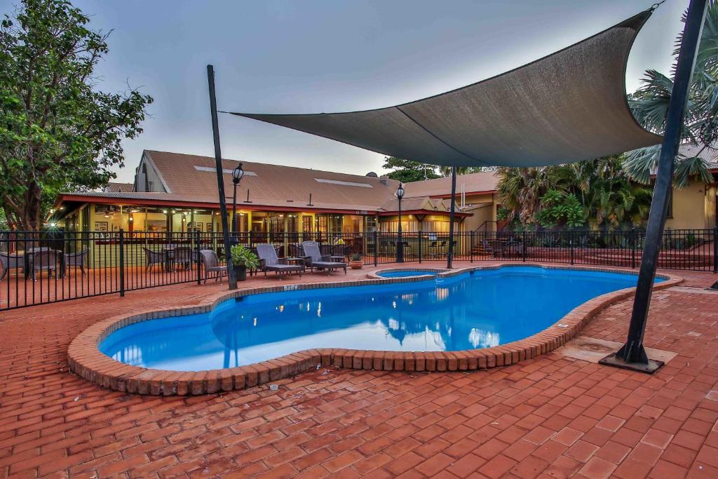 Halls Creek金伯利酒店的大楼前带遮阳伞的游泳池