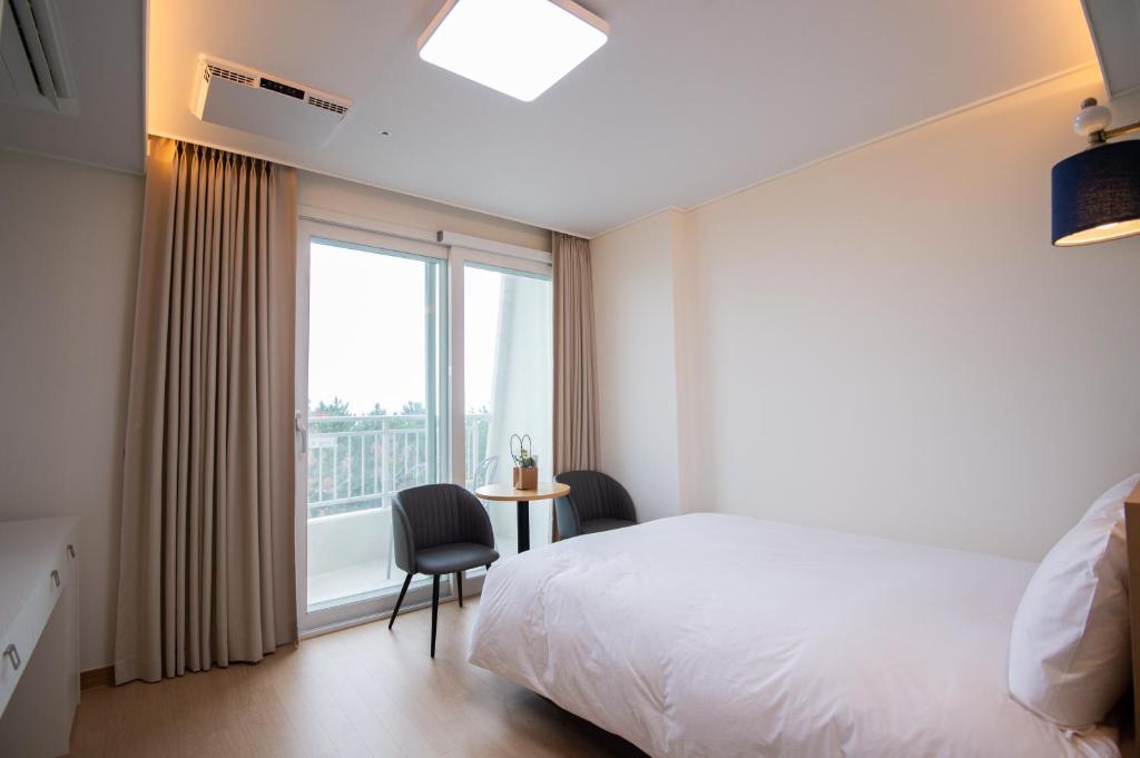 江陵市Gangneung PINEART Label的一间卧室设有一张床、一个窗口和一把椅子