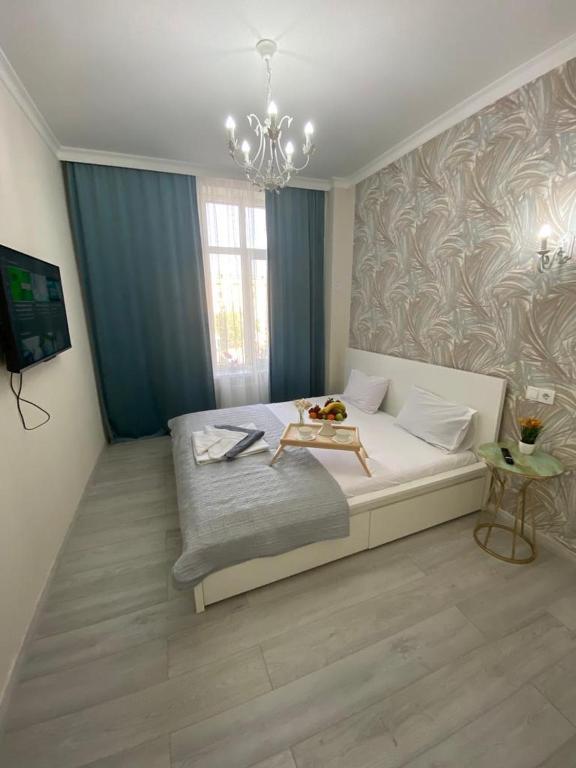 阿特劳Жк Арман двухкомнатная квартира в центре города/ Zhk Arman one-bedroom apartment in the city center的一间卧室配有一张大床和一个吊灯。