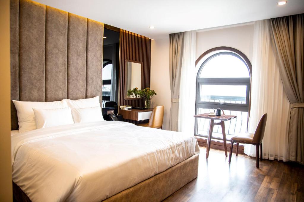 An KhêOstara Hotel & Apartment的一间卧室配有一张床、一张书桌和一个窗户。