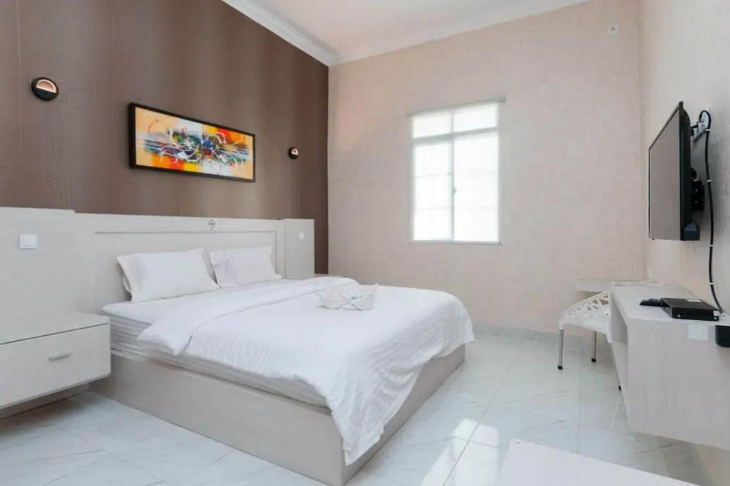 巴拉巴特Hotel 78 Parapat Mitra RedDoorz的白色卧室配有白色的床和书桌