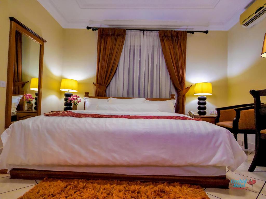 阿克拉Orchid Hotel的卧室设有一张大白色的床和大窗户