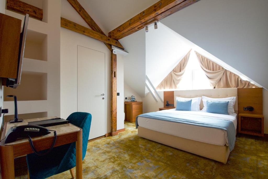 贝尔格莱德萨沃伊城市酒店的一间卧室配有一张床、一张书桌和一个窗户。