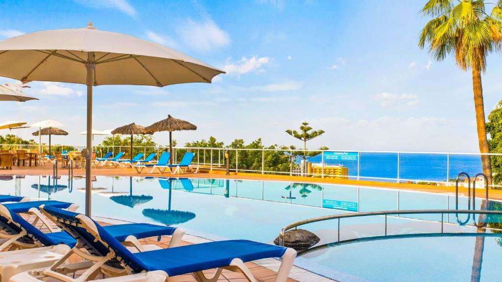 阿德耶Wyndham Residences Costa Adeje的一个带椅子和遮阳伞的度假村游泳池