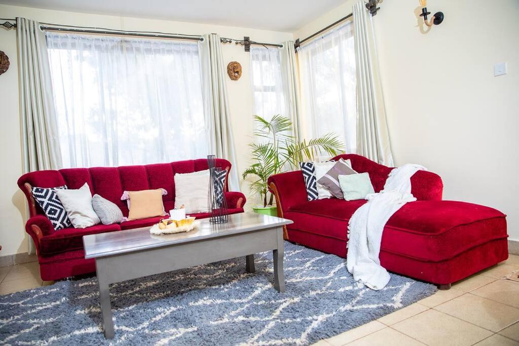 KiambuThe White Dove - At Migaa Golf Estate的客厅配有2张红色沙发和1张咖啡桌